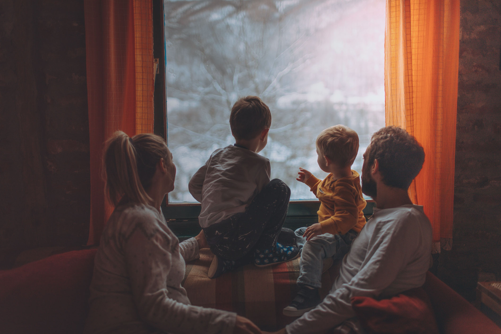 Portrait of a young family with two little boys, and third one on the way, being surprised by snow, early in the morning – right after waking up